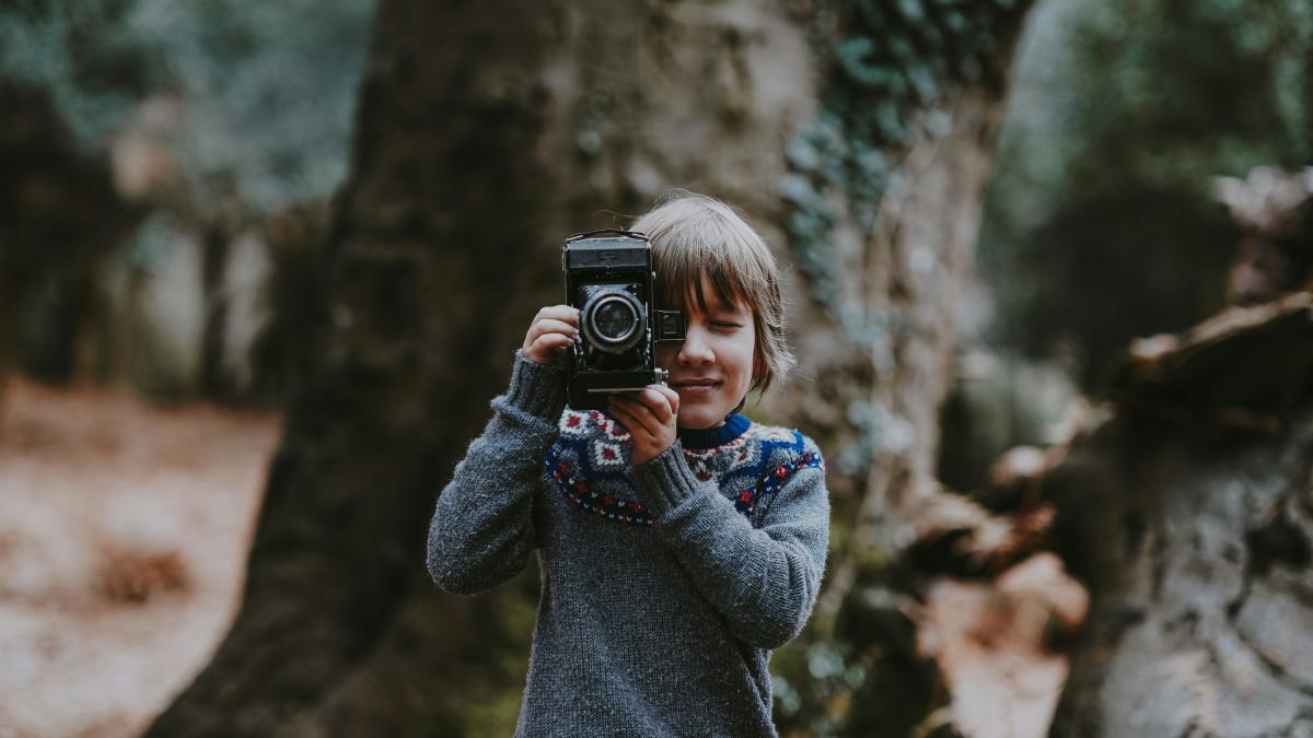 boy holding camera near brown tree during daytime