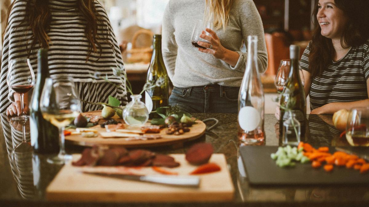 two woman standing beside woman sitting in front of table