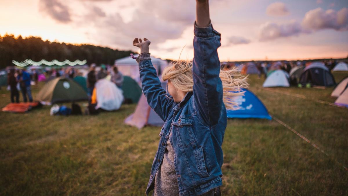 a woman raising her arms in the air in front of tents
