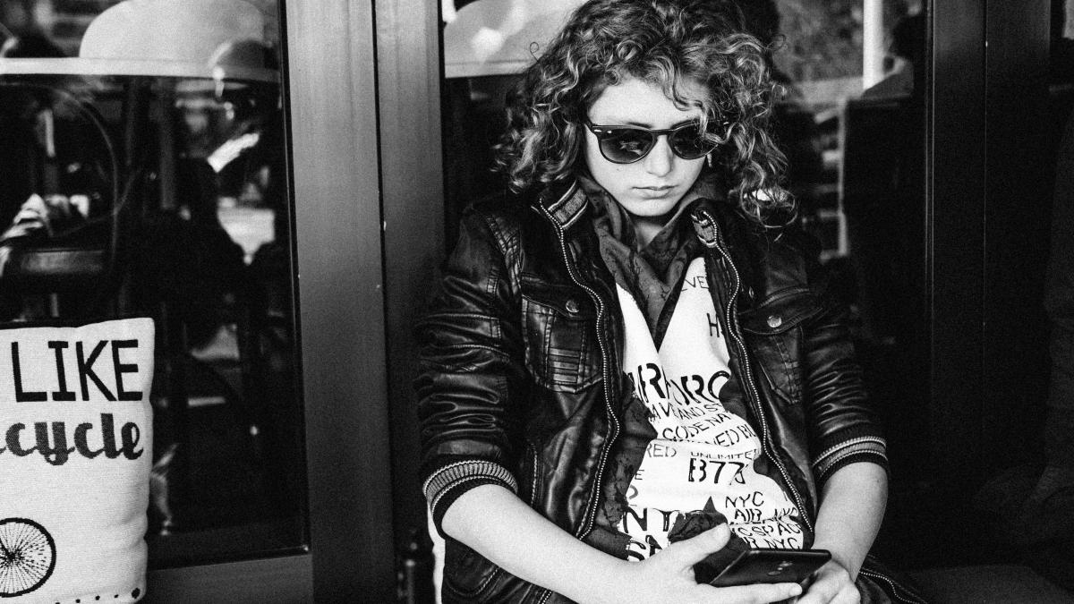greyscale photo of sitting woman using smartphone