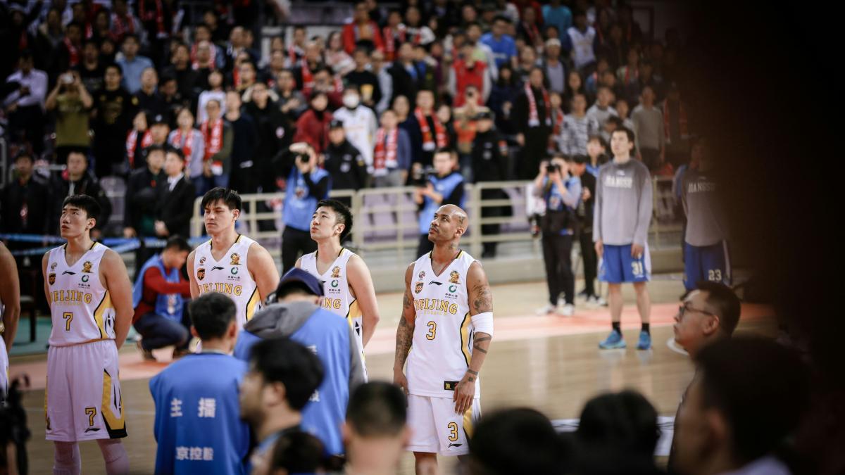 four basketball players forming a line while standing on court surrounded by crowd