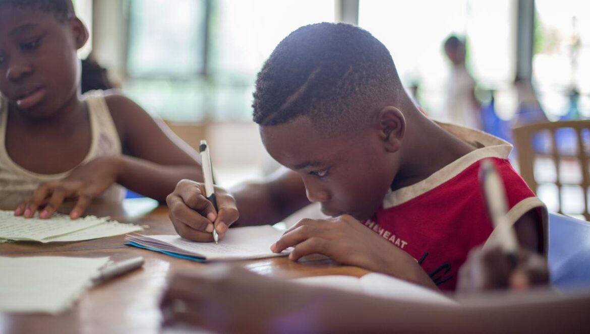 boy writing on printer paper near girl