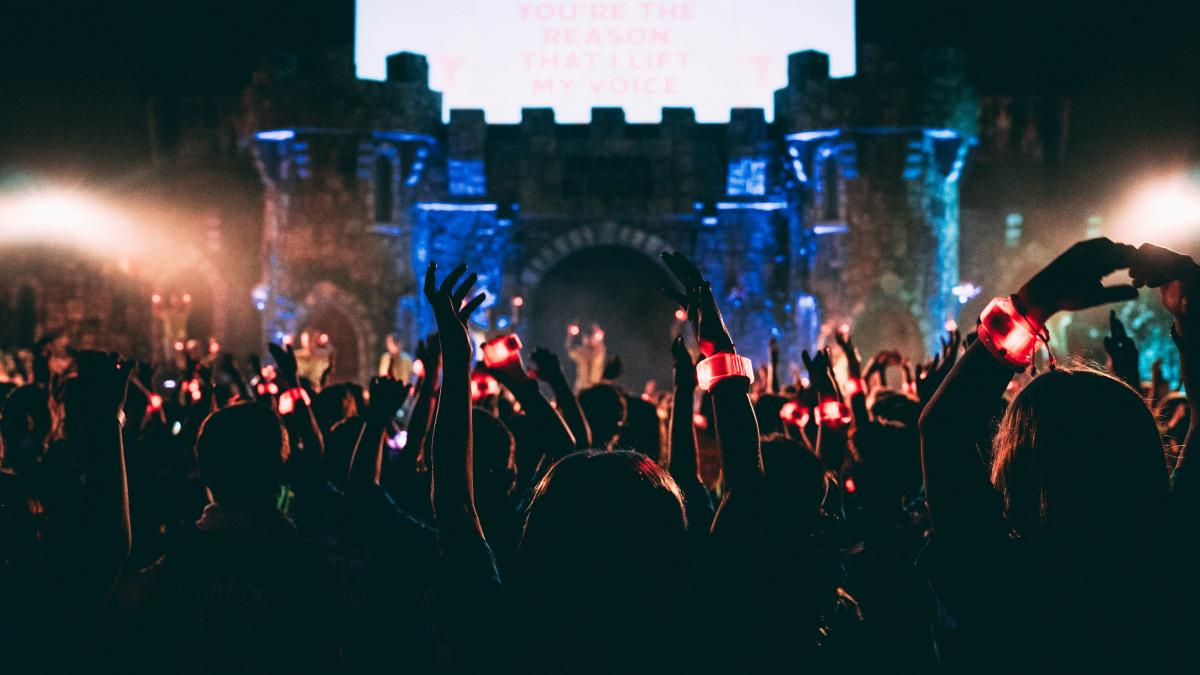 crowded people wearing LED bracelet raising hands in front of stage
