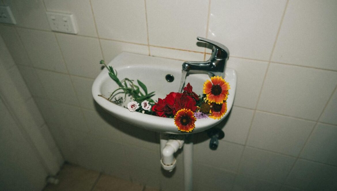 variety of flowers in white ceramic pedestal sink
