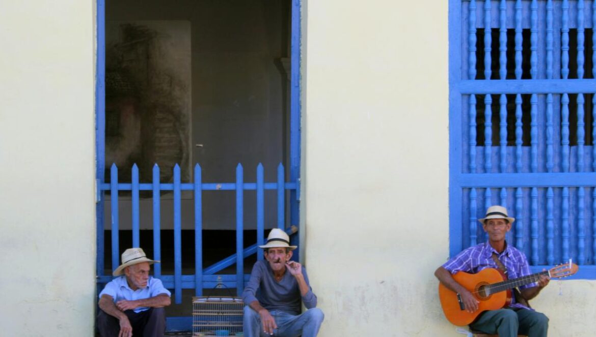 three men sitting near white building