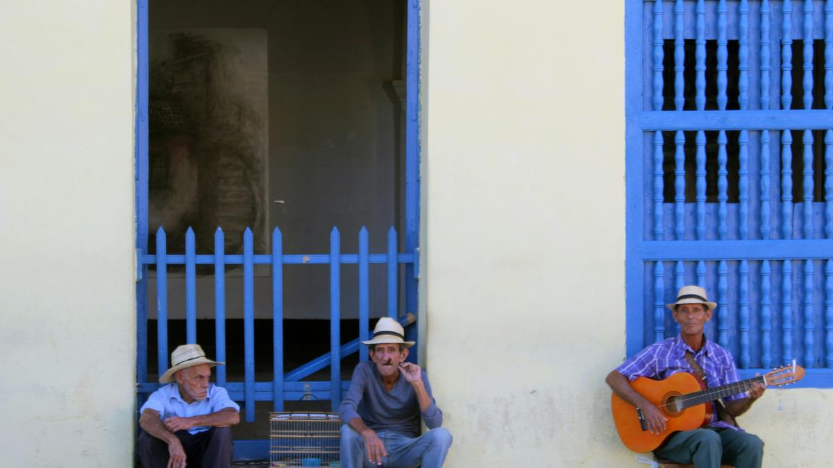 three men sitting near white building