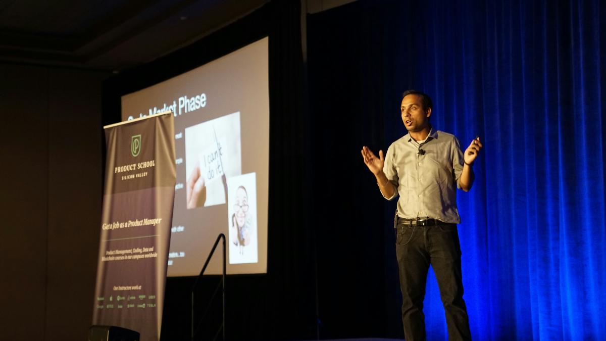 man standing in stage beside blue curtain