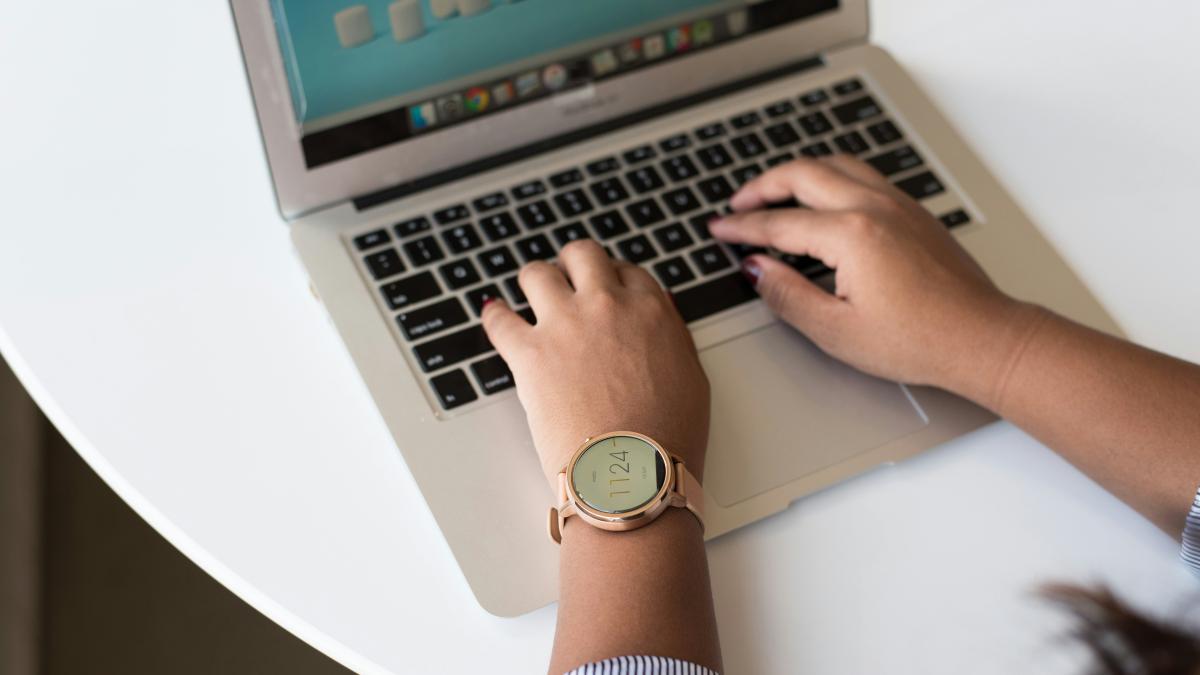 person using MacBook on white table