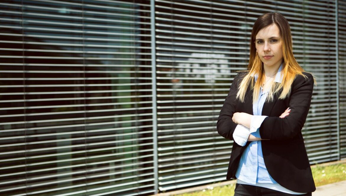 woman in black blazer standing near window blinds
