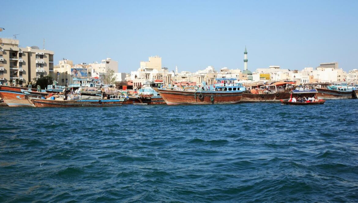 brown boat on sea near city buildings during daytime