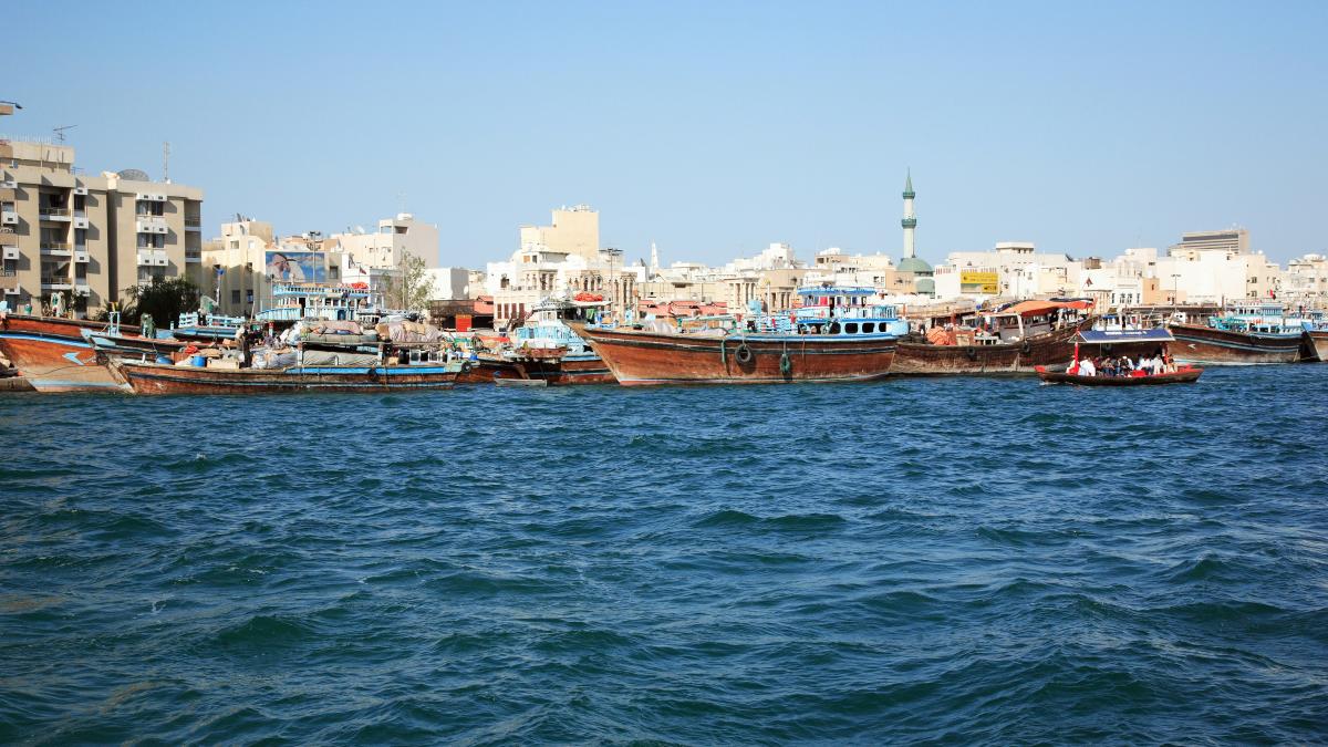 brown boat on sea near city buildings during daytime
