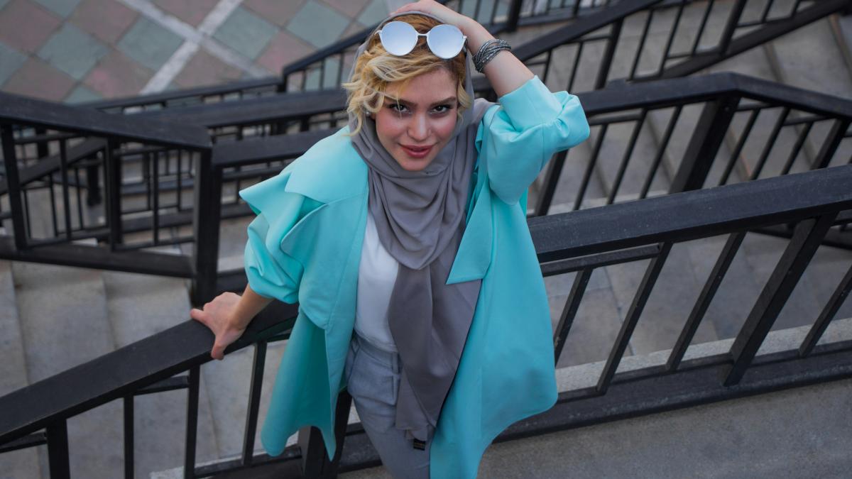 woman in blue coat wearing black sunglasses