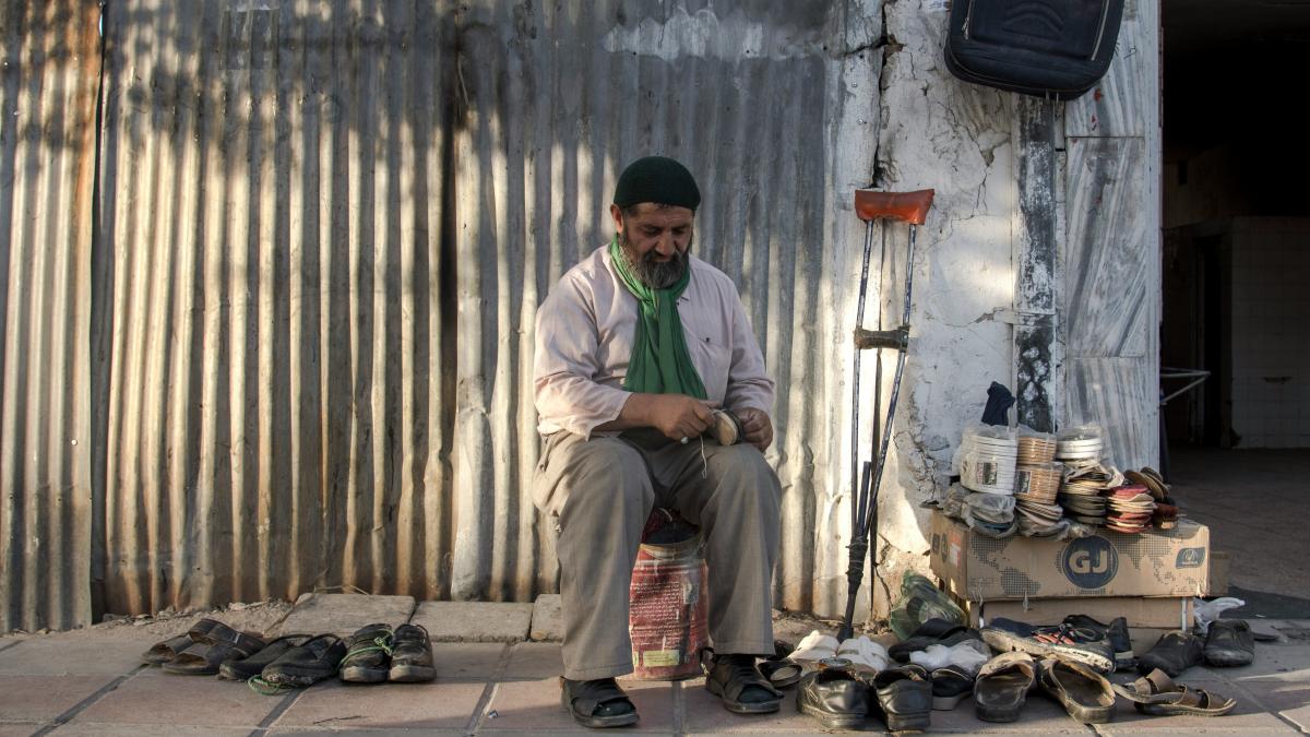 man in green dress shirt and brown pants sitting on chair