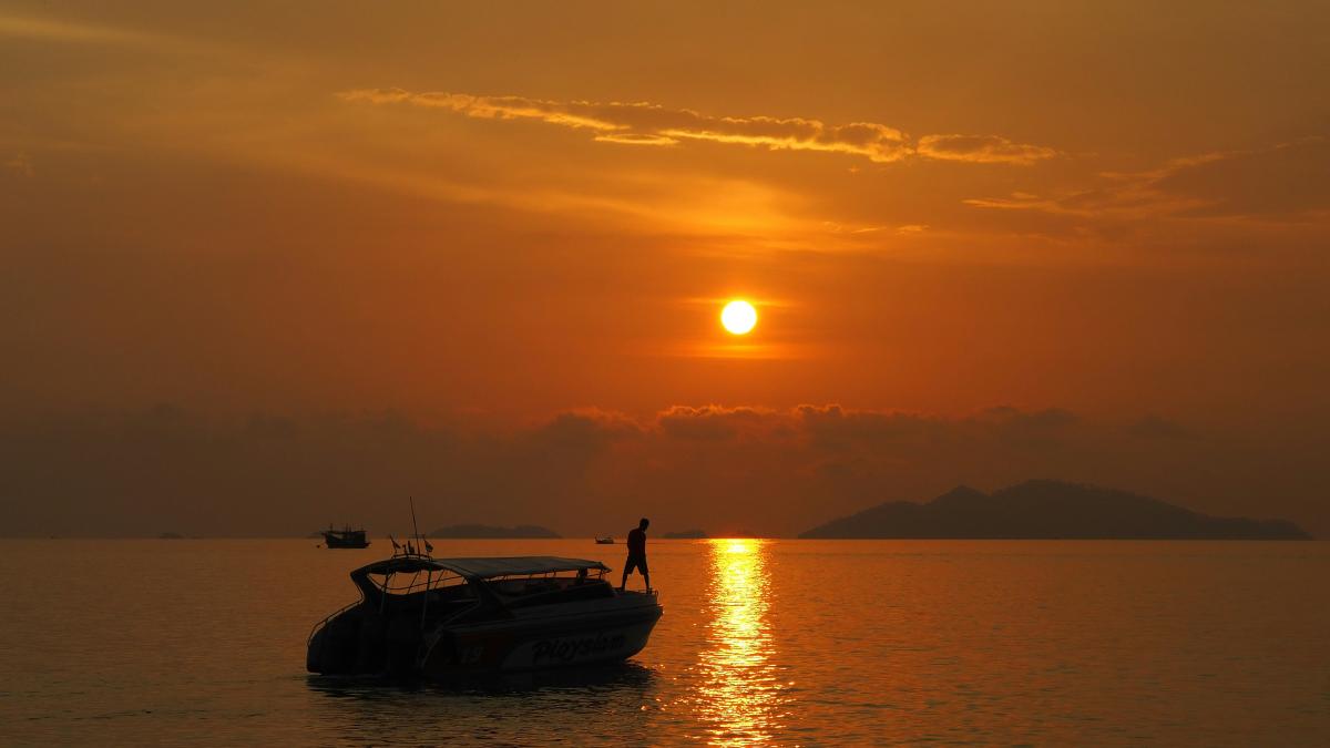 silhouette of boat on sea during sunset