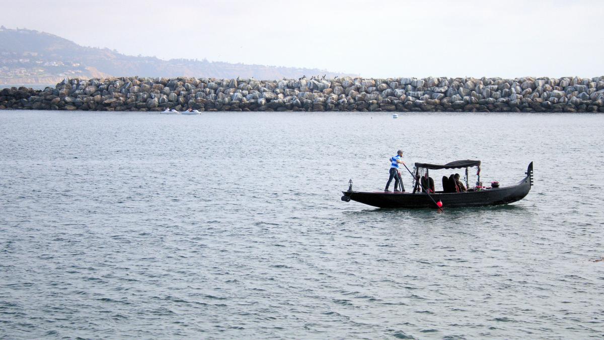 a man standing on the back of a boat in the water