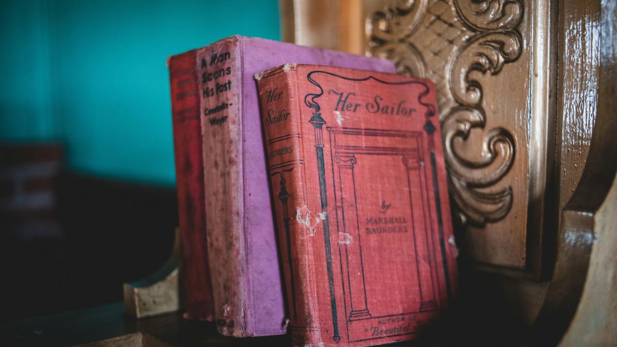 red hardbound book on brown wooden table