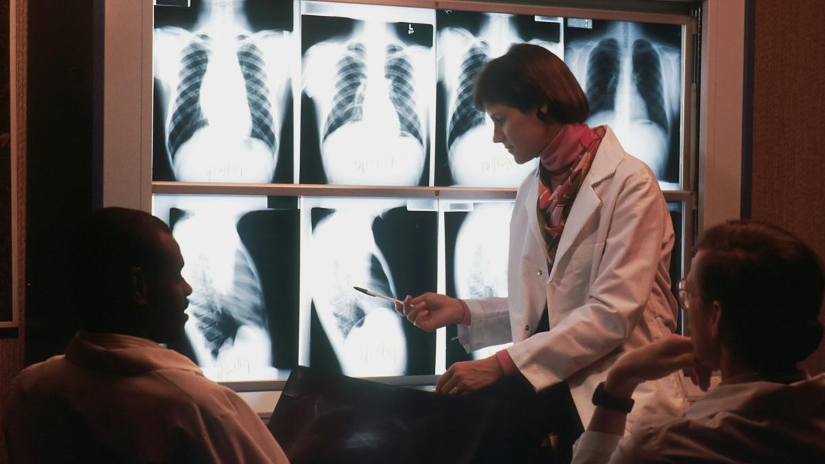 a doctor talking to a patient in front of a x - ray
