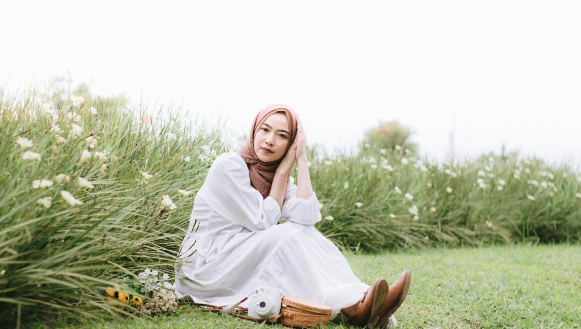 a woman in a white dress sitting in a field