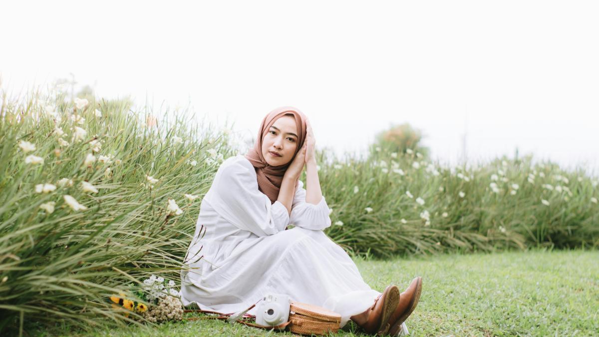 a woman in a white dress sitting in a field