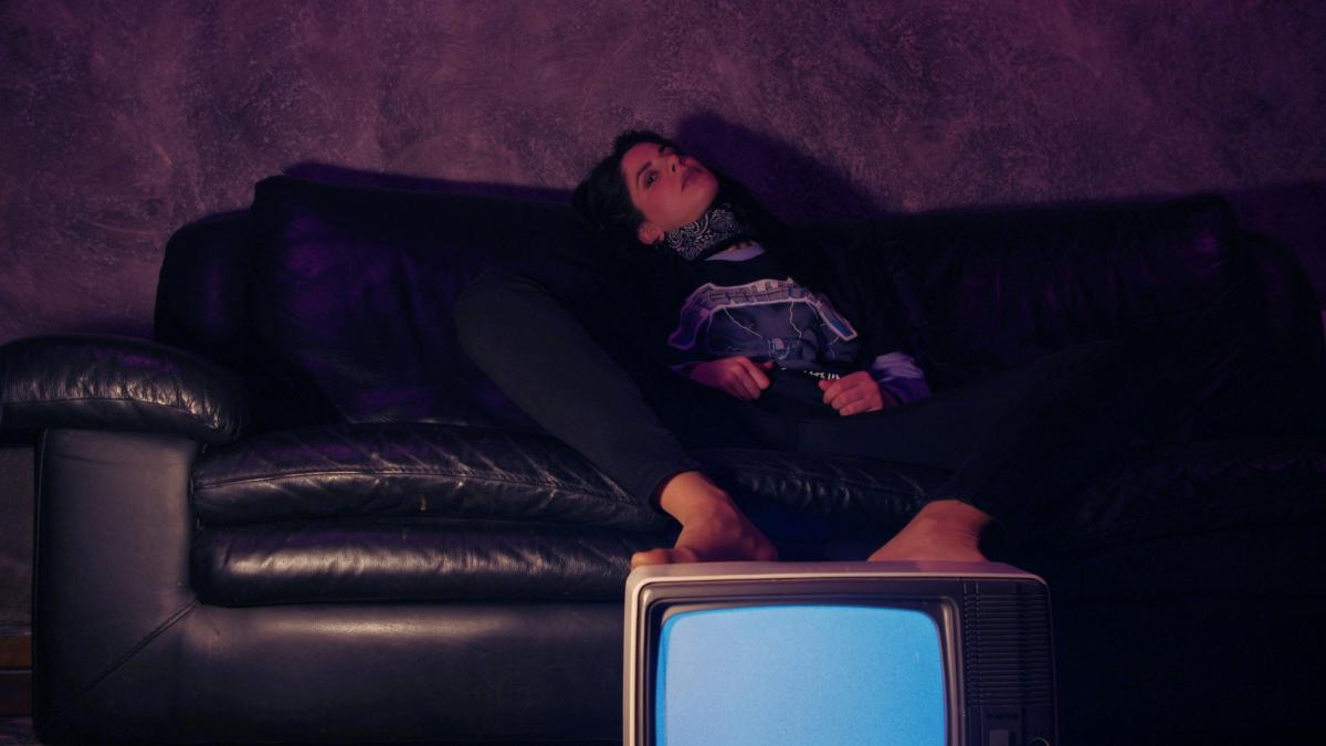 a woman sitting on a couch next to a tv
