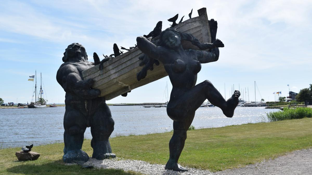 a statue of a group of people holding hands by a body of water