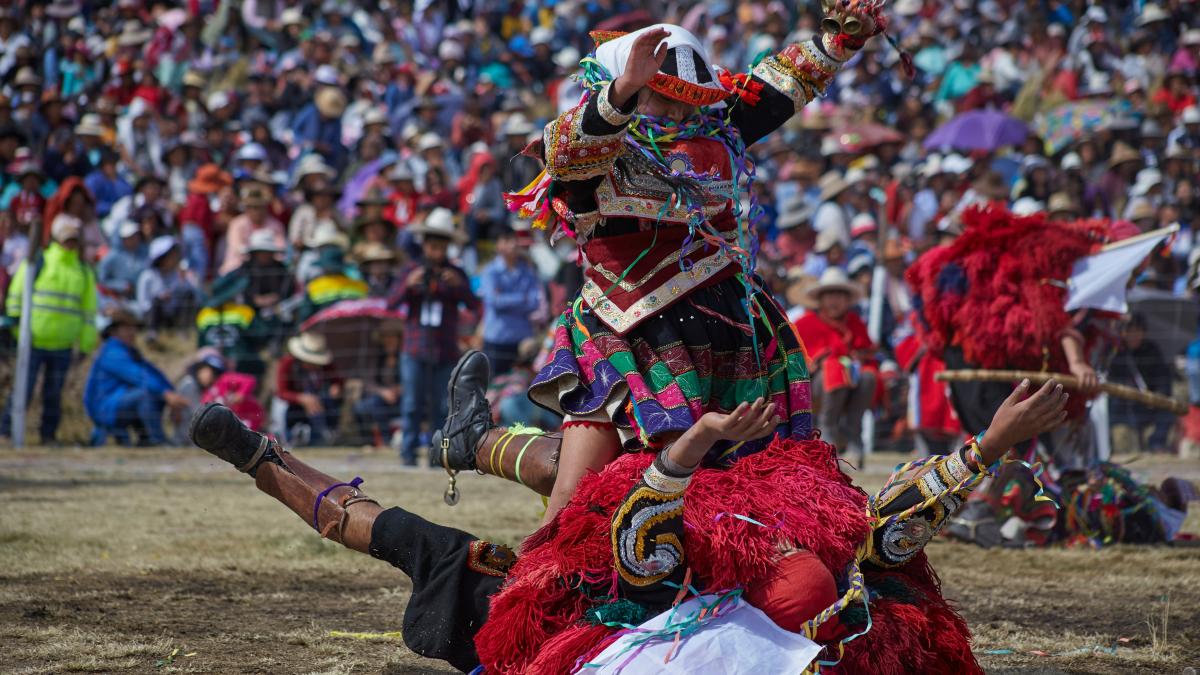 a person in a garment holding a sword in front of a crowd