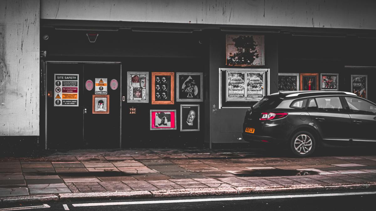 a car parked in front of a building with posters on the wall