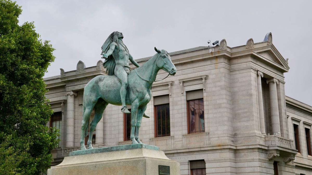 a statue of a person riding a horse in front of a building