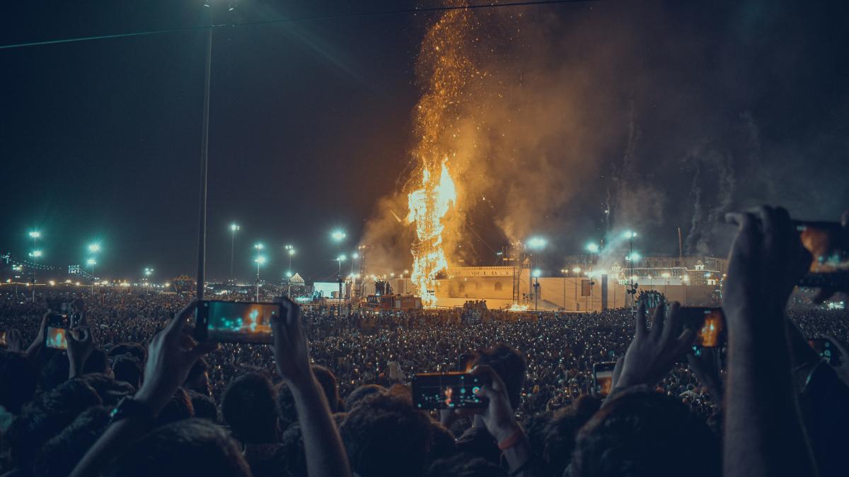 a crowd of people watching a stage with fireworks in the background