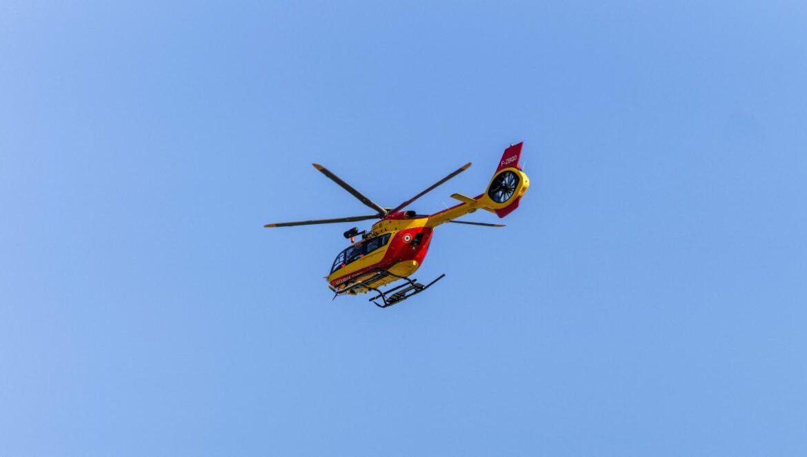 a red and yellow helicopter flying through a blue sky