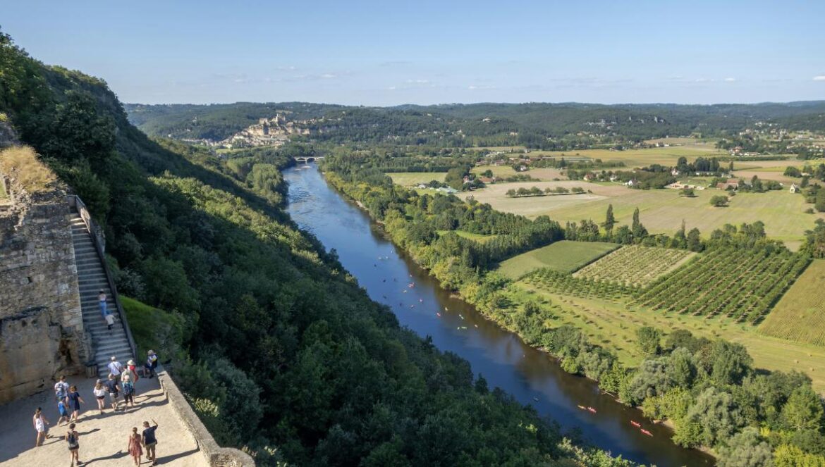 a group of people standing on top of a cliff next to a river