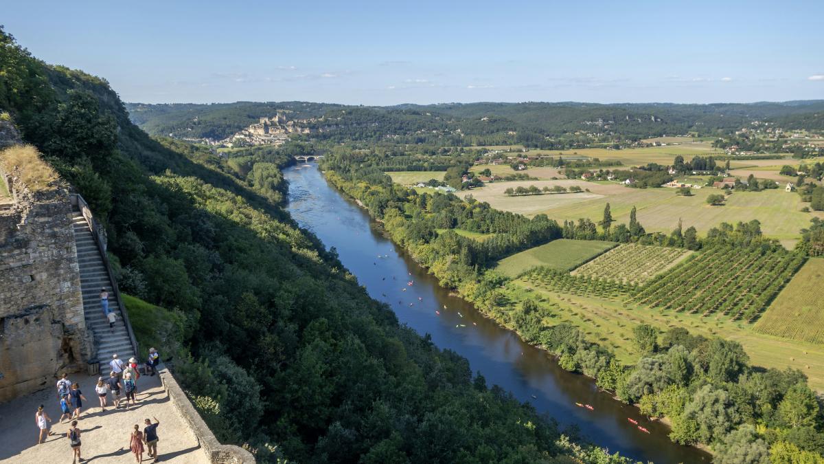 a group of people standing on top of a cliff next to a river
