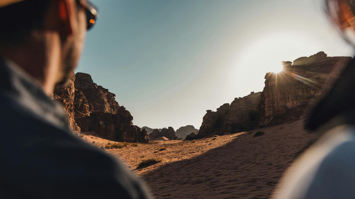 a man standing in the desert looking at the sun