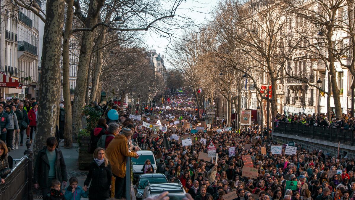 a crowd of people walking down a street next to tall buildings