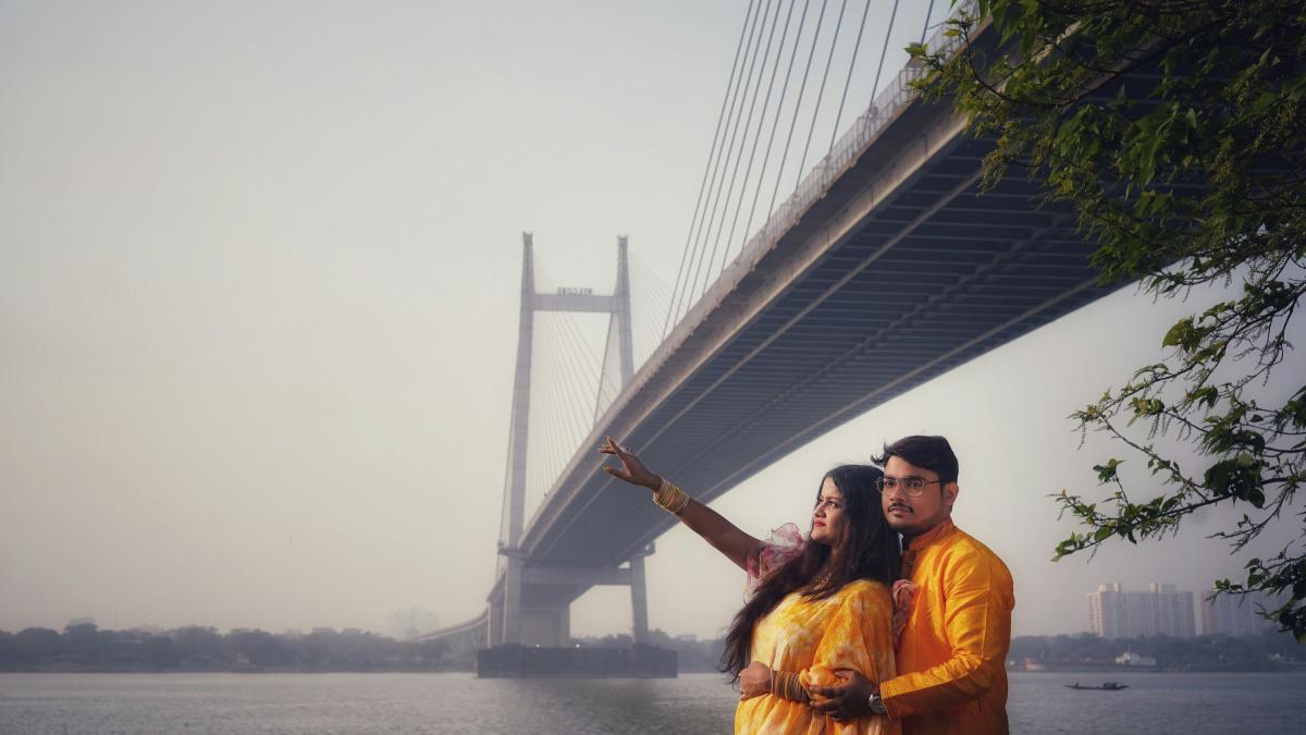 a man and a woman standing in front of a bridge