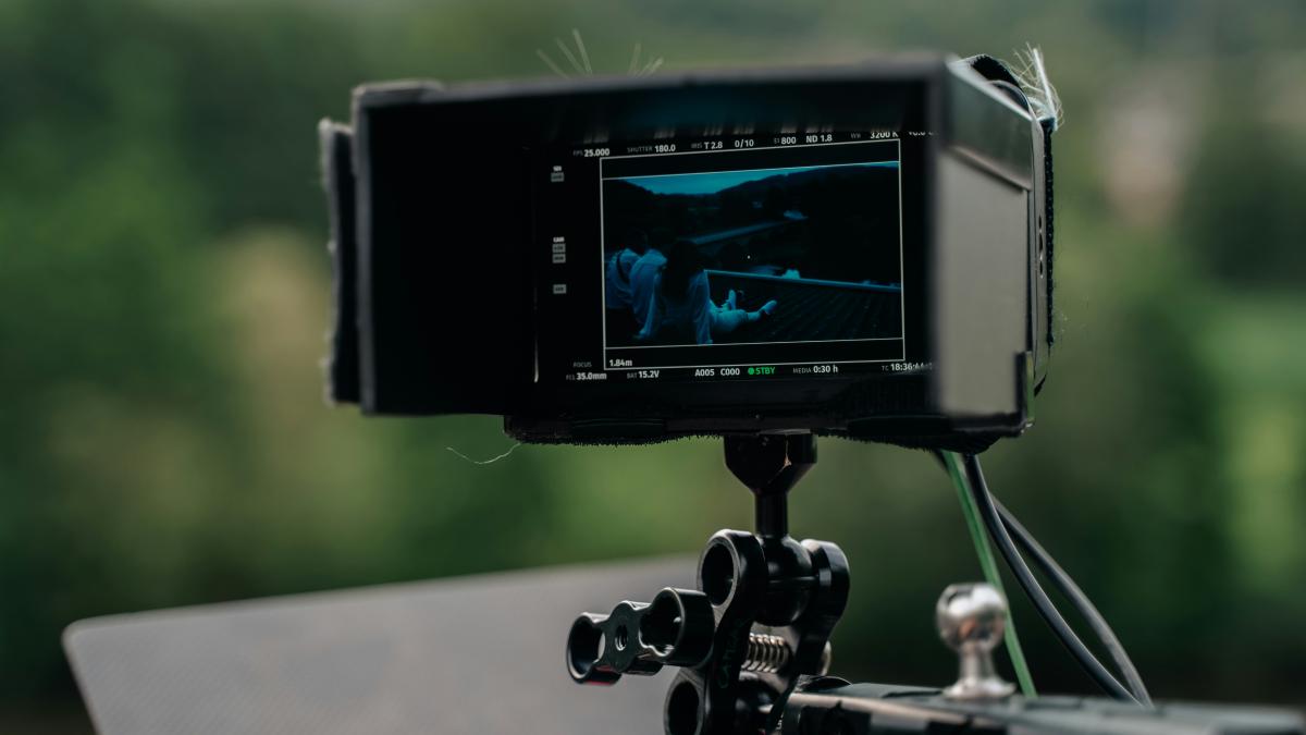 a video camera attached to a tripod with trees in the background