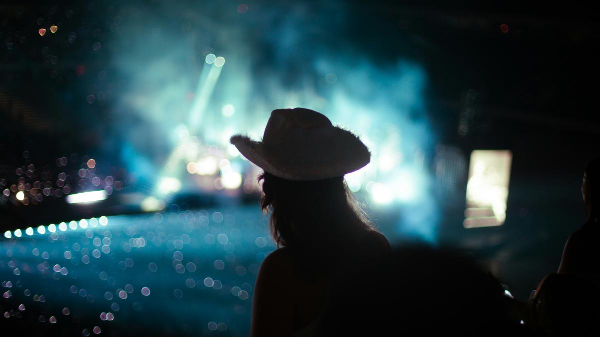 a woman in a cowboy hat standing in front of a stage