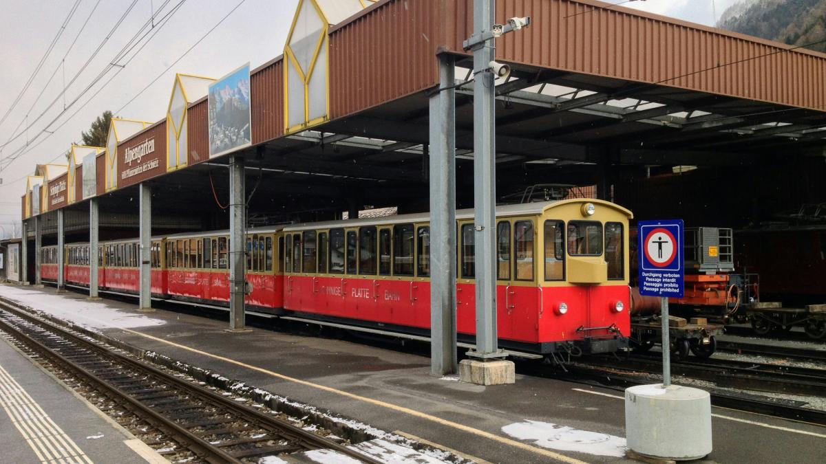 a red and yellow train pulling into a train station