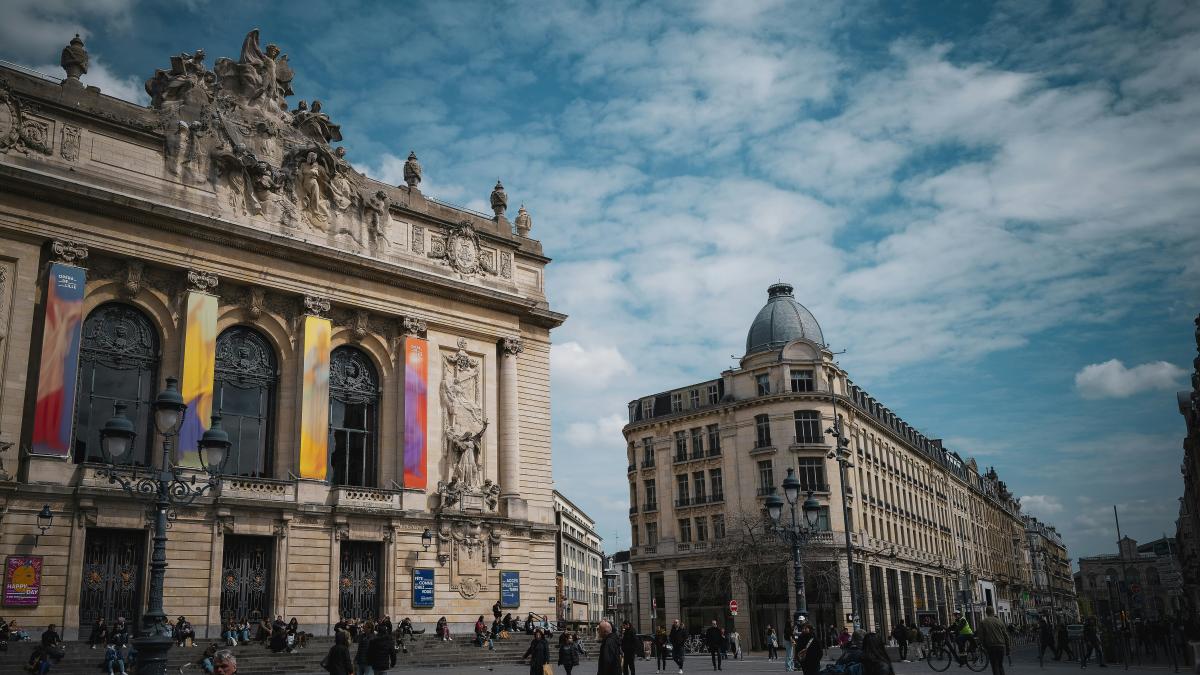 a group of people walking down a street next to tall buildings