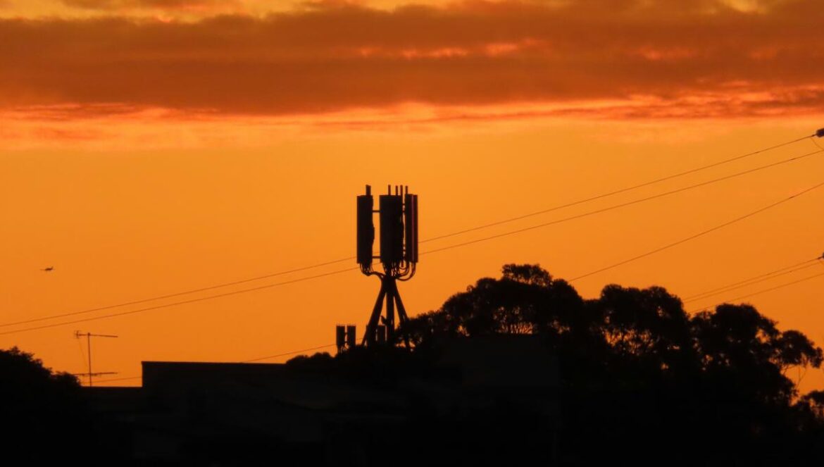a sunset with a cell phone tower in the foreground