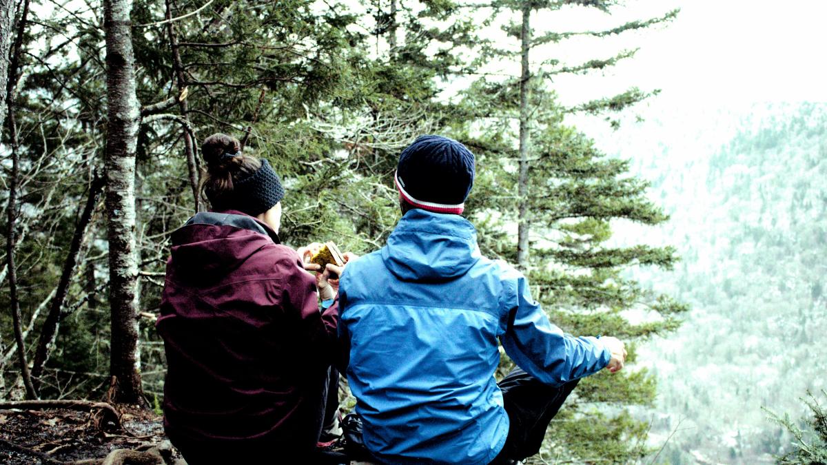 two people sitting on a rock in the woods