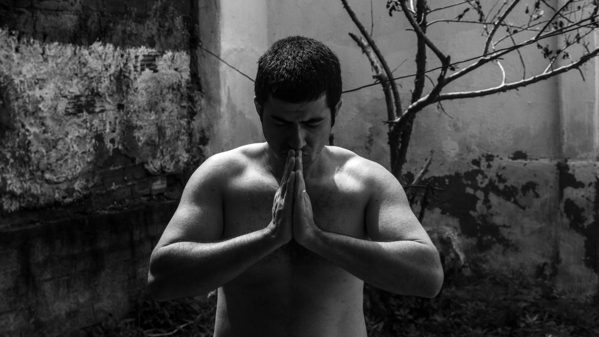 a shirtless man standing in front of a tree