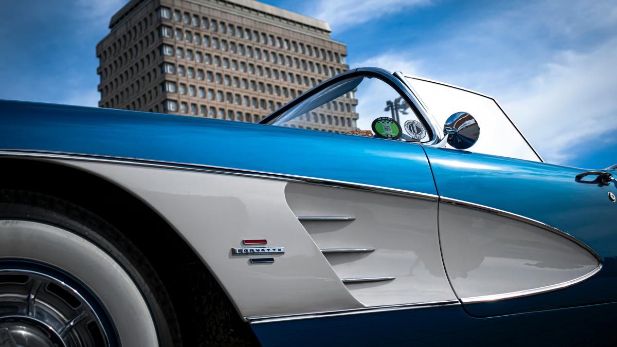 a blue and white car parked in front of a tall building