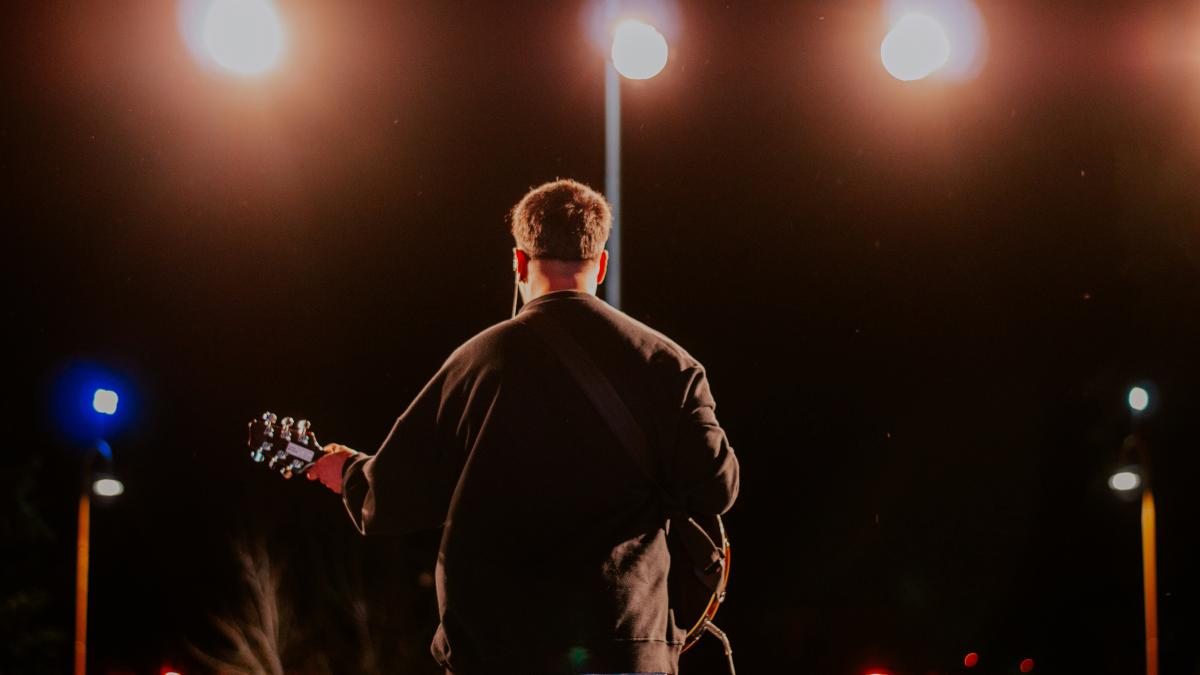 a man standing on a stage playing a guitar