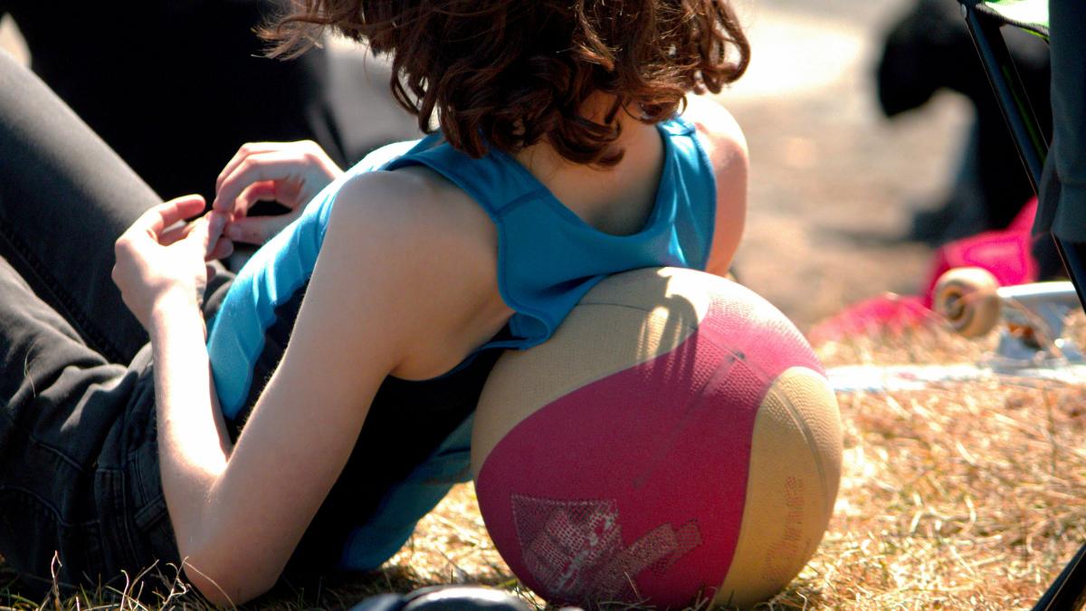 a little girl sitting on the ground with a ball