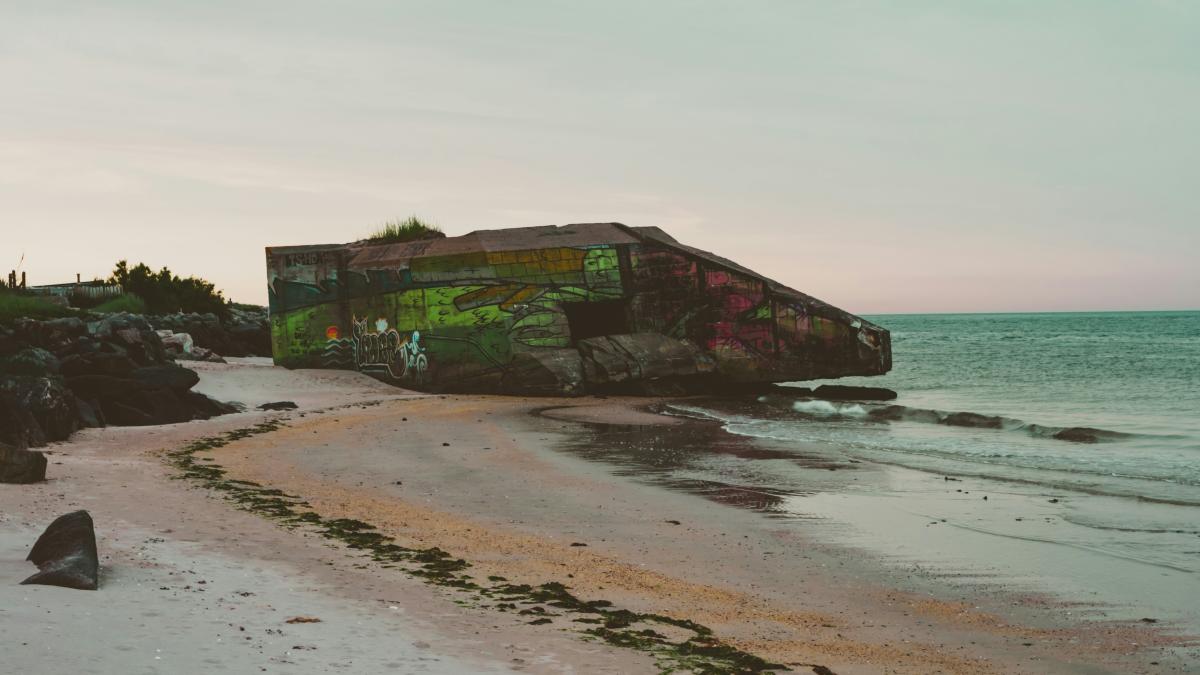 A boat sitting on top of a sandy beach next to the ocean