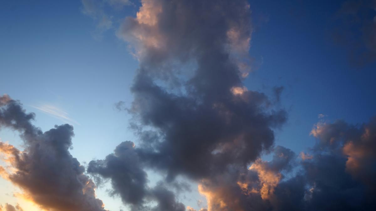 The sun is setting behind some clouds in the sky