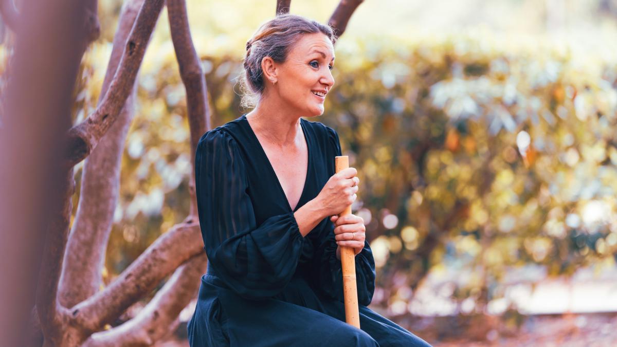 A woman sitting on a bench holding a stick