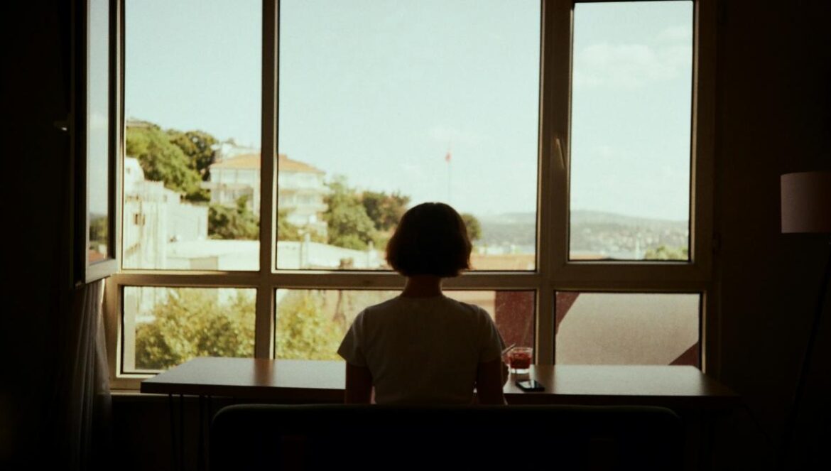 A person sitting at a table looking out a window