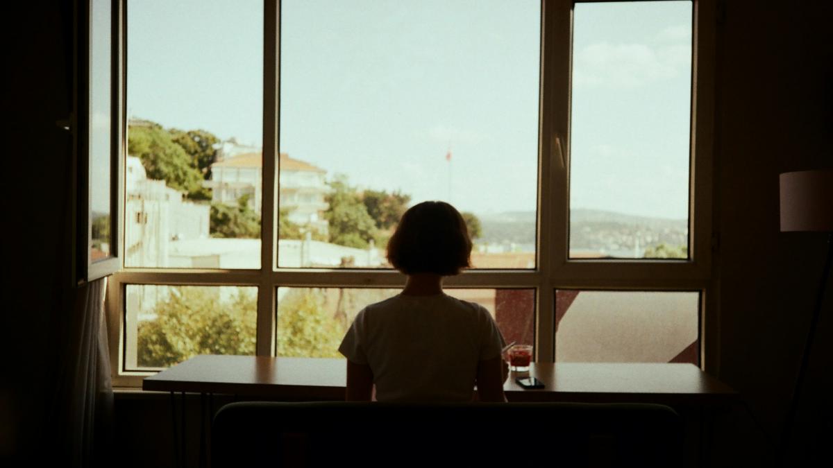 A person sitting at a table looking out a window